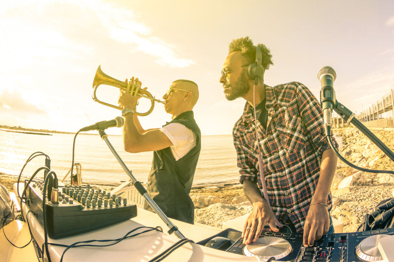 Dj bei Sonnenuntergang Beach Party mit Trompet-Jazz-Interpret